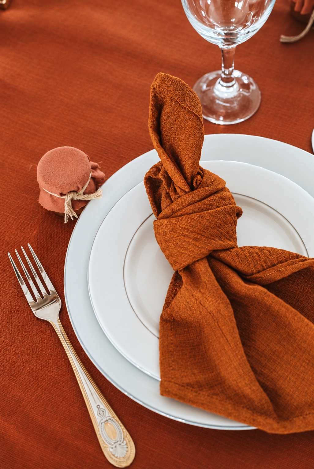 Détail d’une place de table terracotta avec serviette nouée