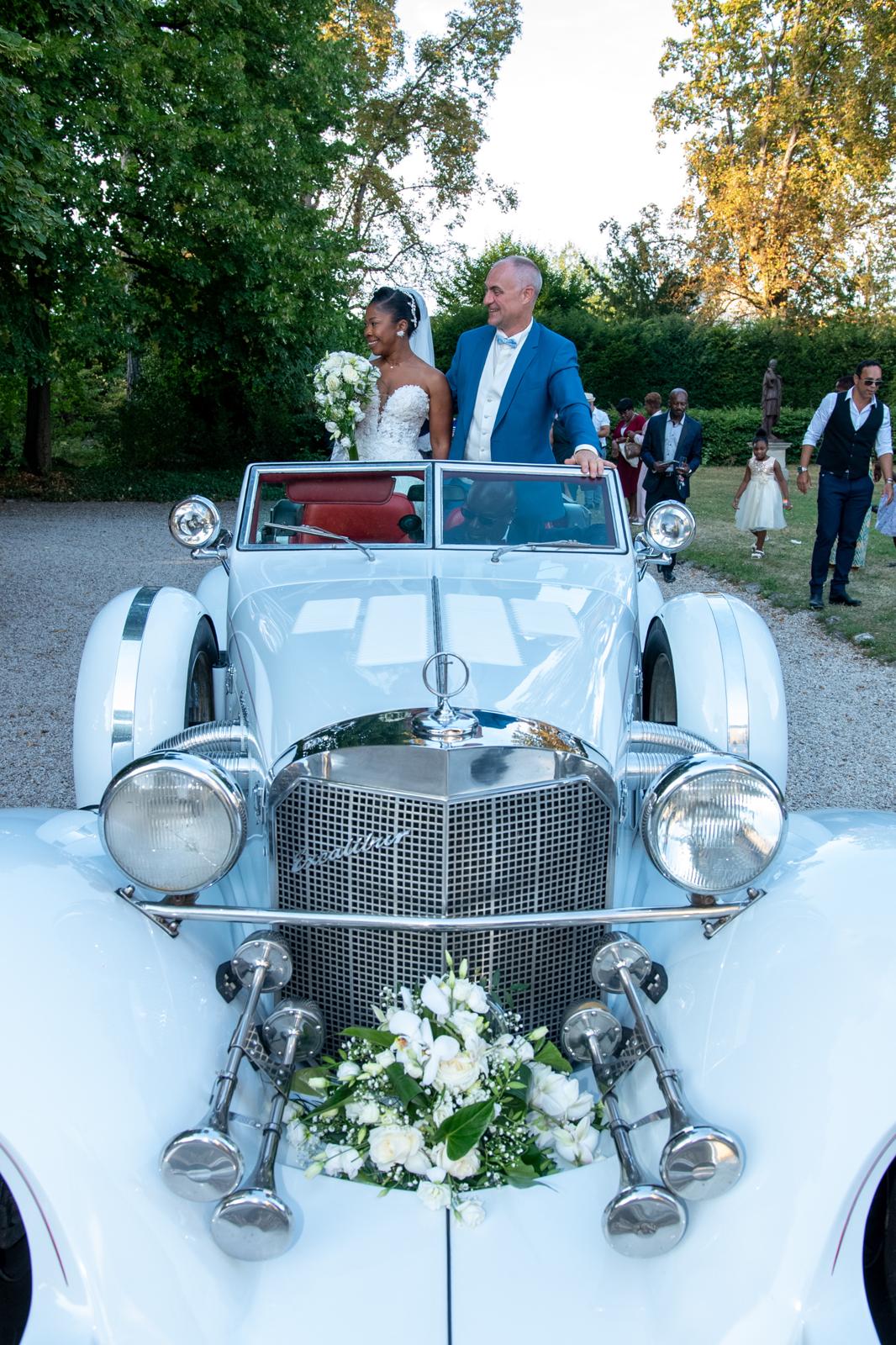 Couple de mariés dans une voiture de cérémonie fleurie
