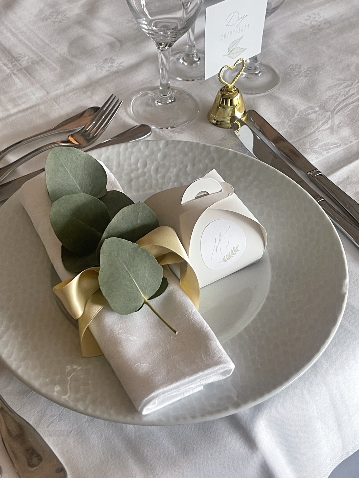 Art de la table élégant avec eucalyptus, ruban doré et vaisselle blanche