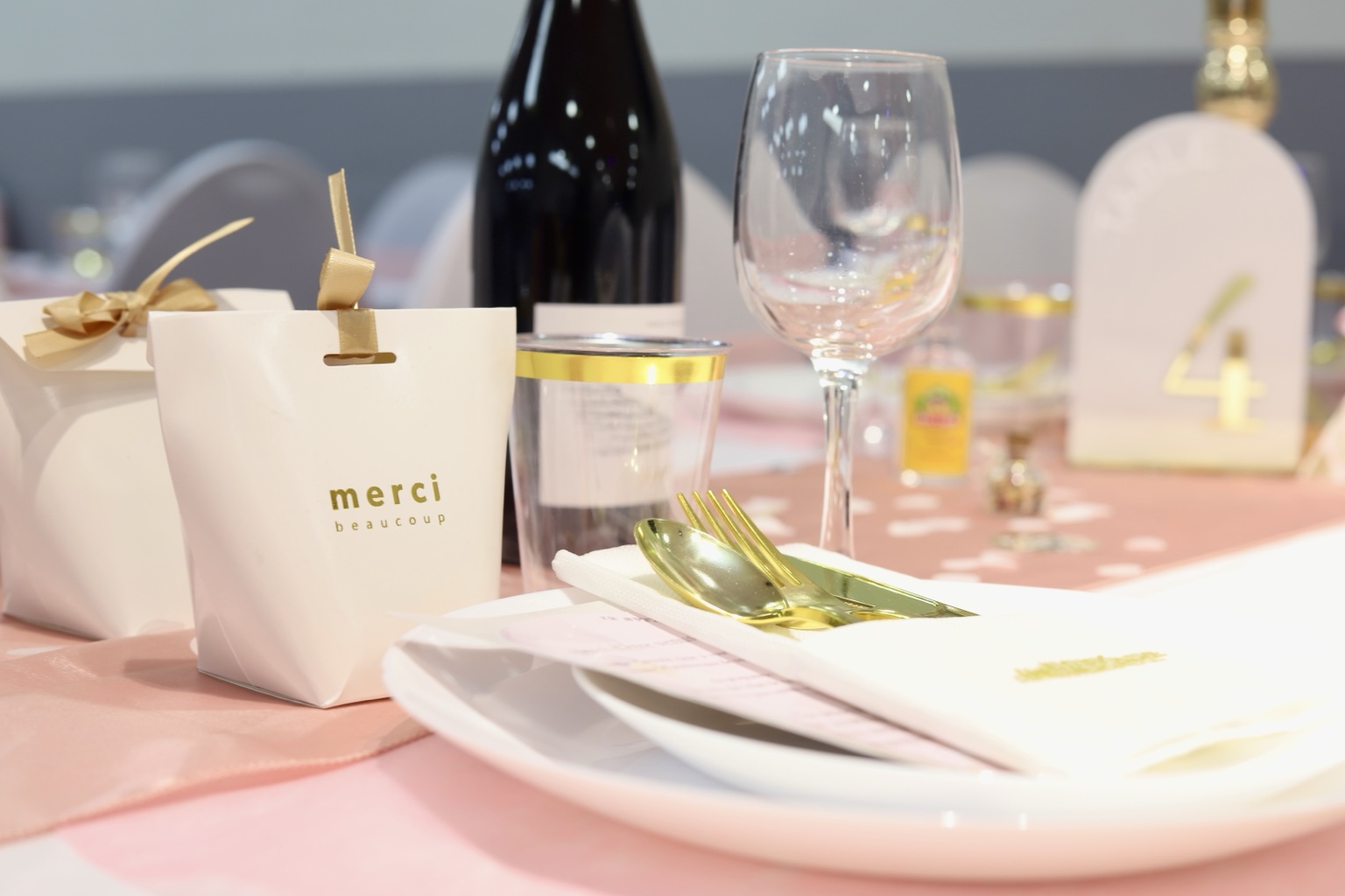 Détail d’une table rose, blanche et dorée avec cadeau d’invité